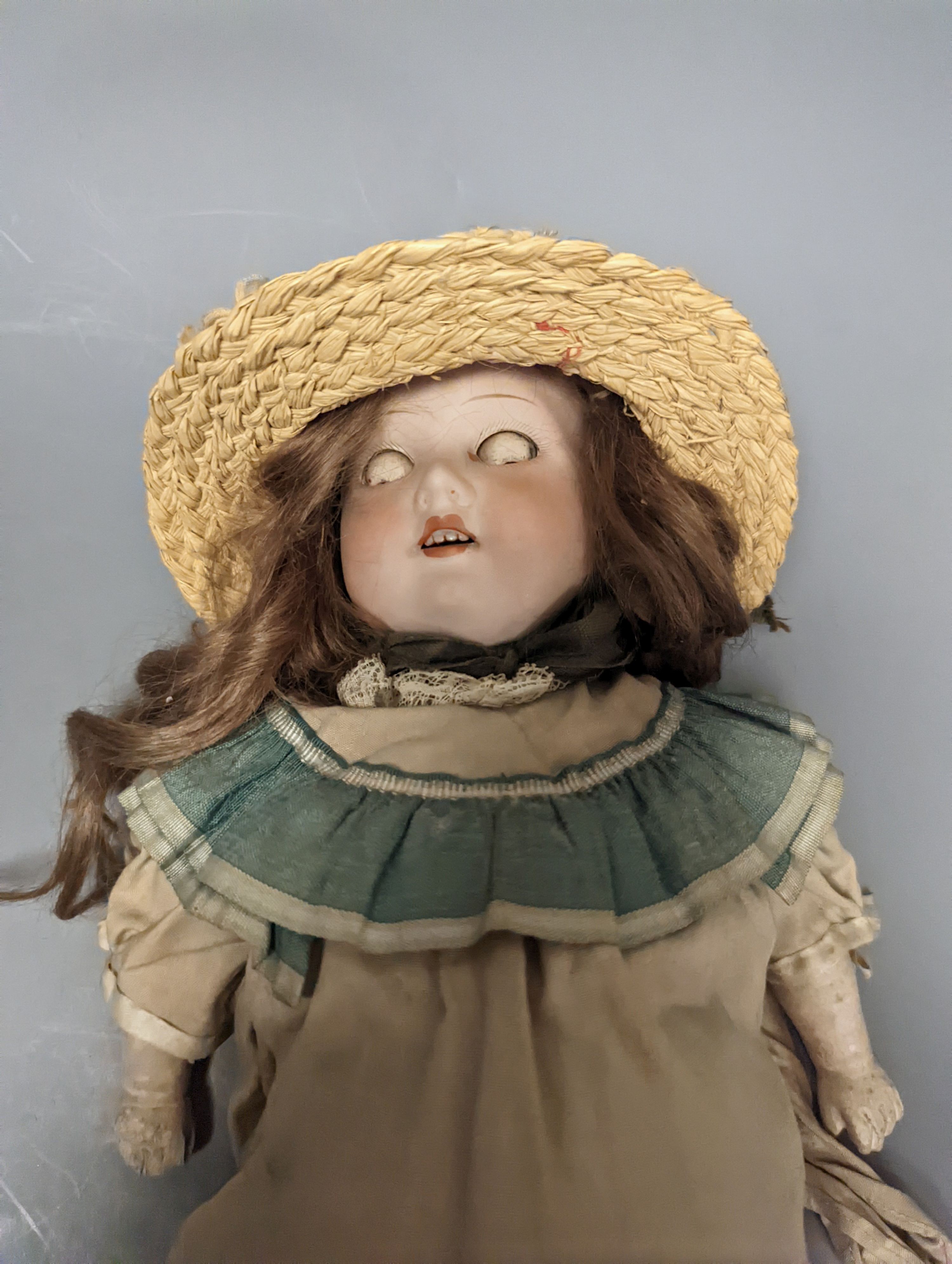 An Armand Marseille 370 bisque headed doll, wearing a basket weave boater and brown embroidered dress, 44cms high.